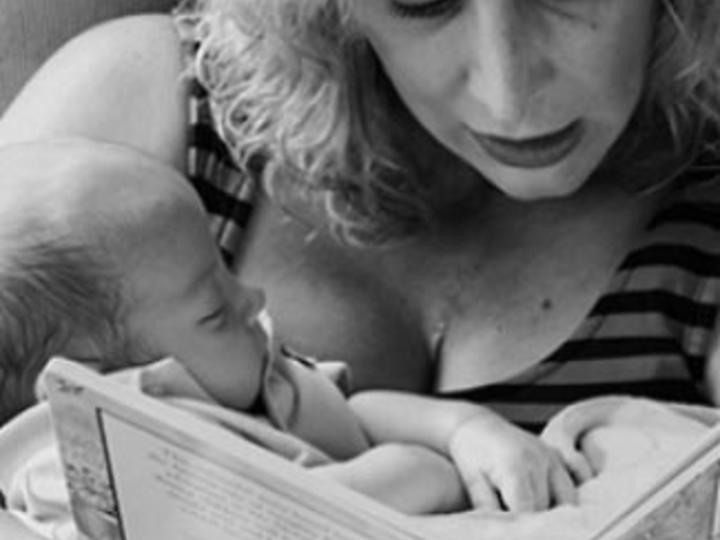 Mother holds baby and reads baby a book