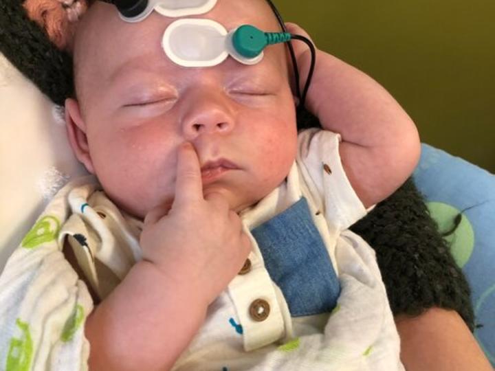 baby with hearing screening monitors attached