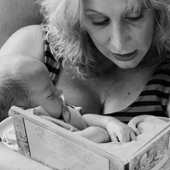 Mother holds baby and reads baby a book